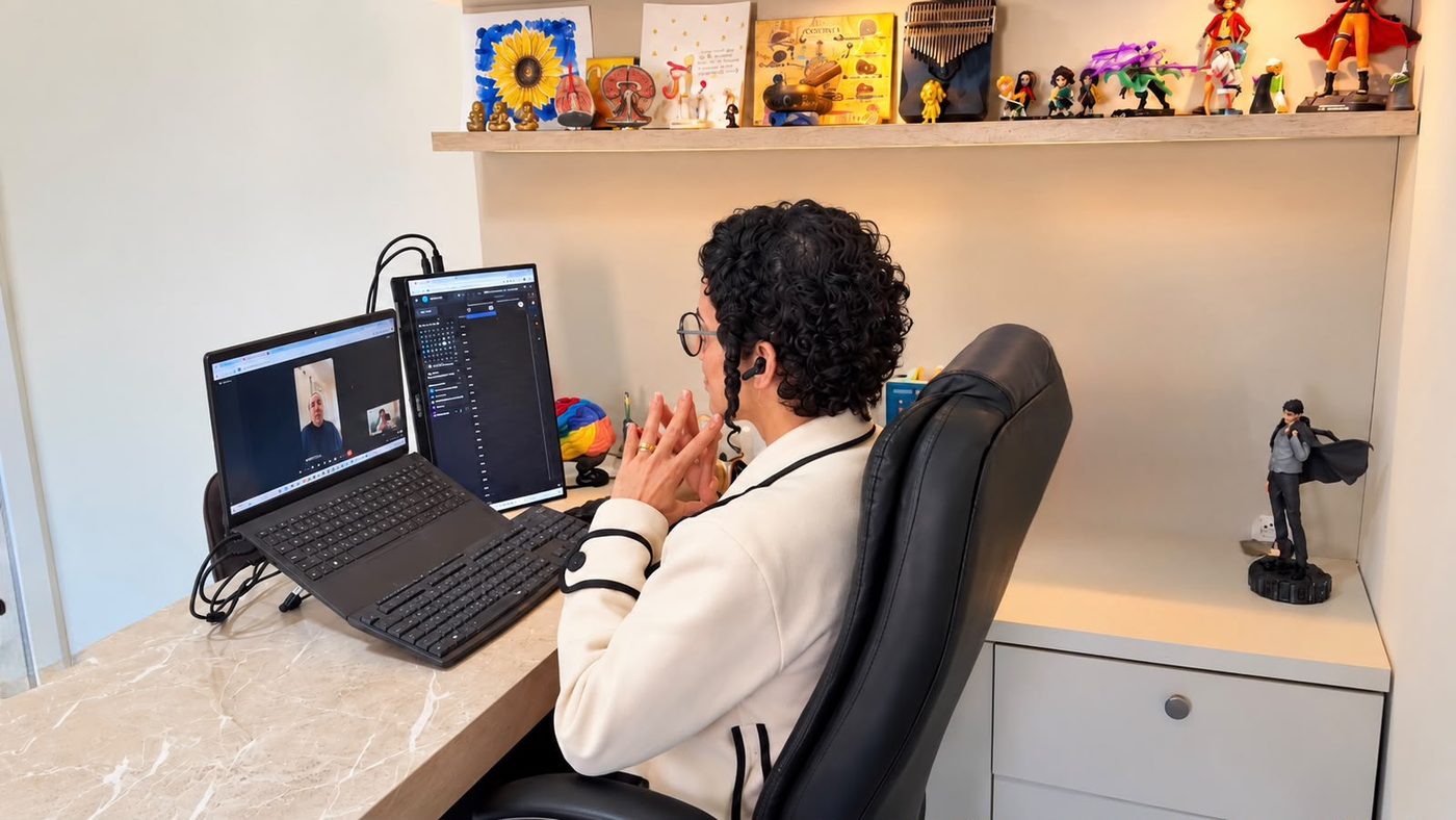 Aline Vicente em seu consultório conduzindo uma avaliação neuropsicológica por videochamada; a pessoa na tela é modelo