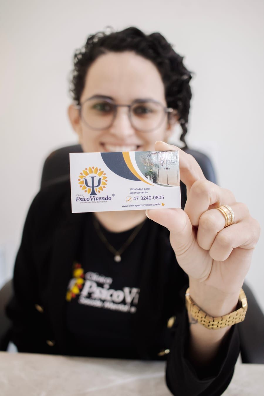Aline Vicente mostrando o cartão da Clínica PsicoVivendo