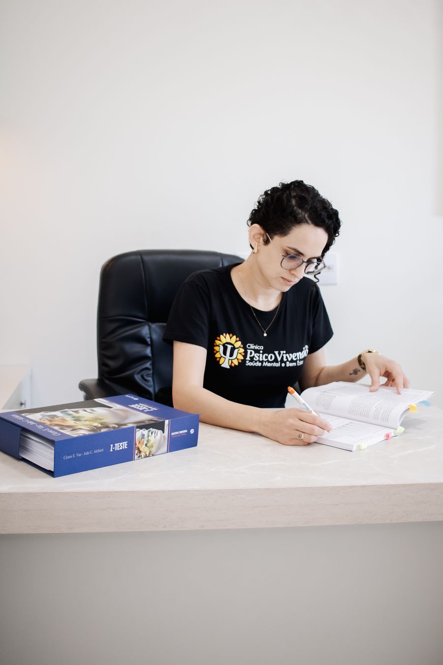 Aline Vicente, neuropsicóloga, corrigindo testes em sua mesa no consultório